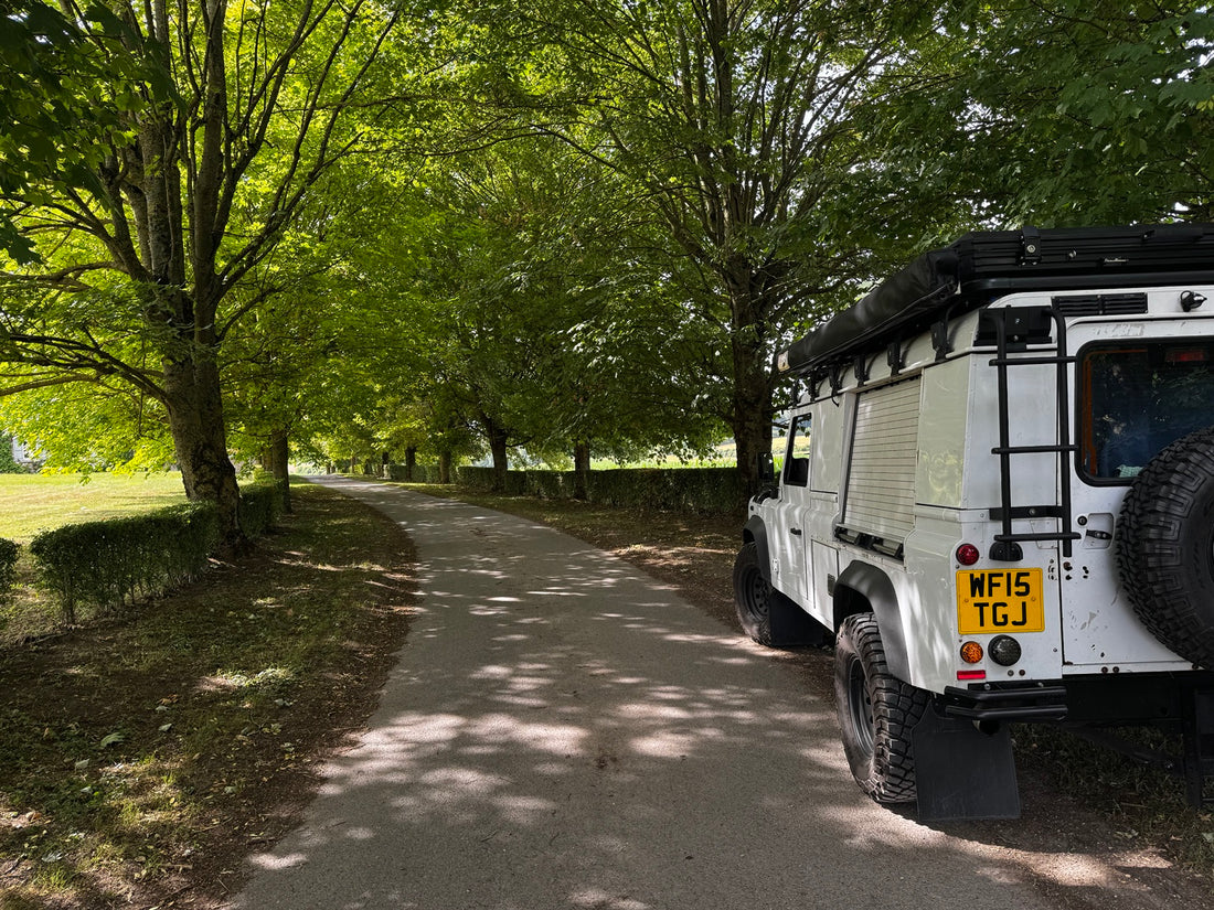Criddle Overland Land Rover Defender parked beside a tree-lined country road