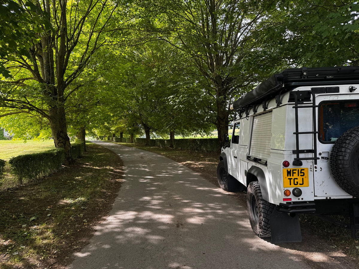 Criddle Overland Land Rover Defender parked beside a tree-lined country road
